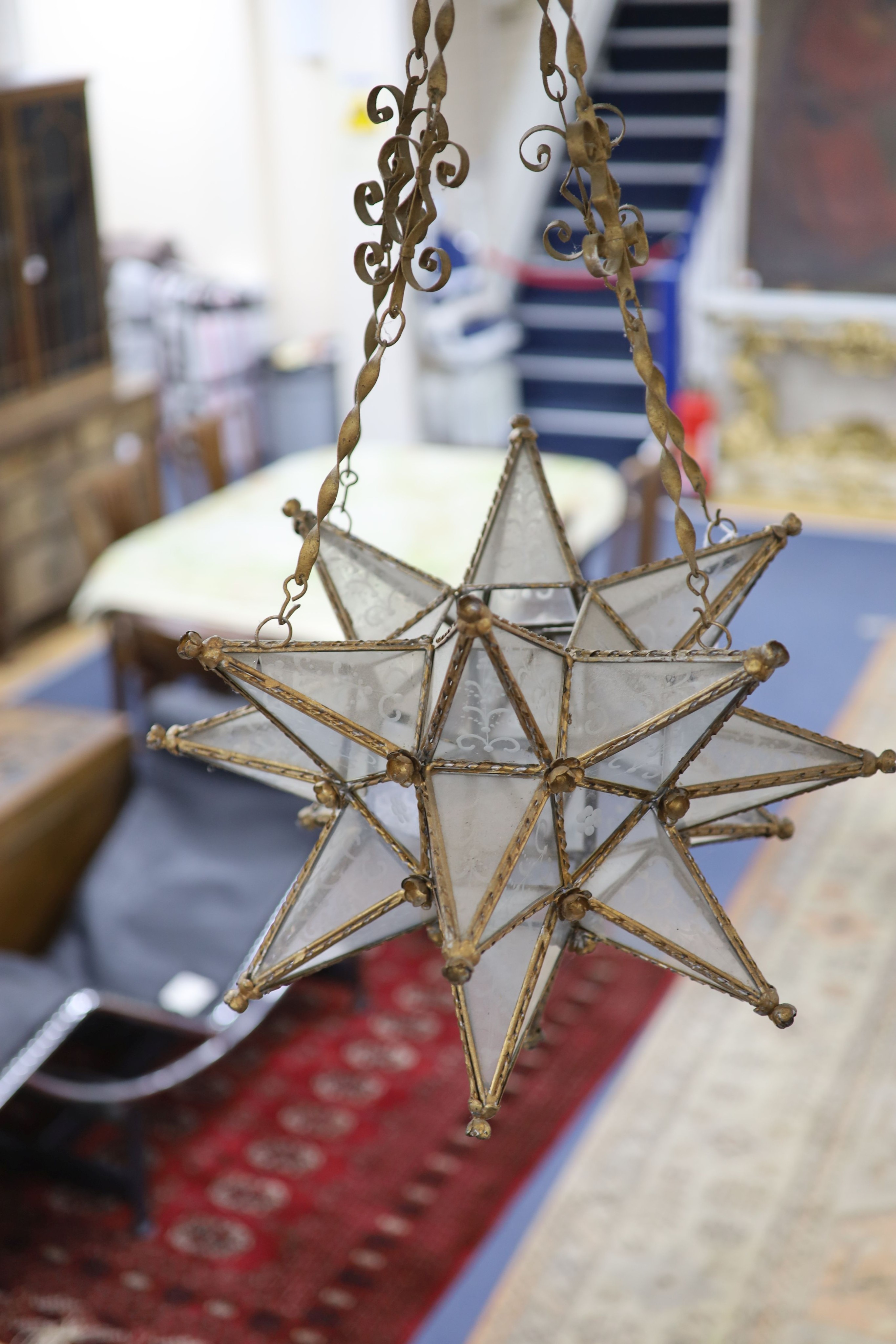 A gilt-metal star-shaped ceiling light, having etched plain glass panels and chain suspension, height 80cm